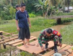 Bantu Kesulitan Rakyat, Babinsa Koramil 04/Jawai Bantu Warga Perbaiki Jembatan Penyeberangan Orang.